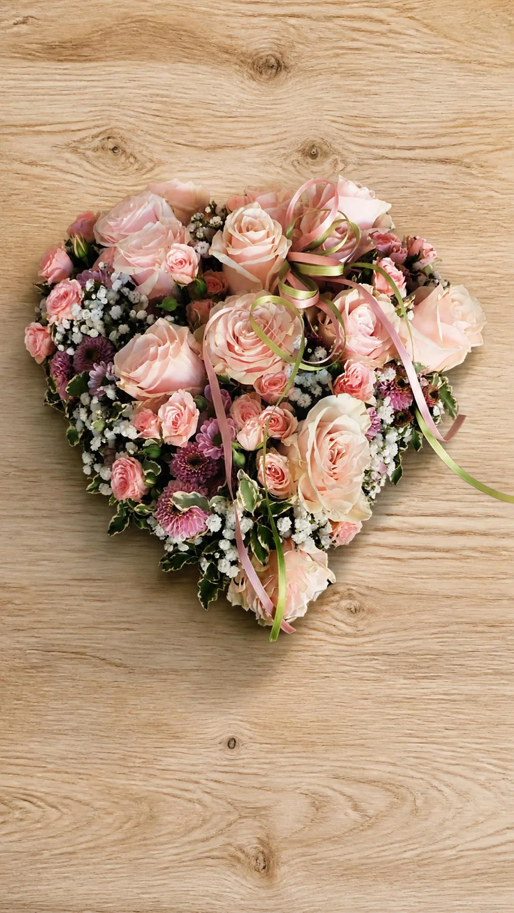 Cuore floreale rosa appoggiato su una superficie in legno